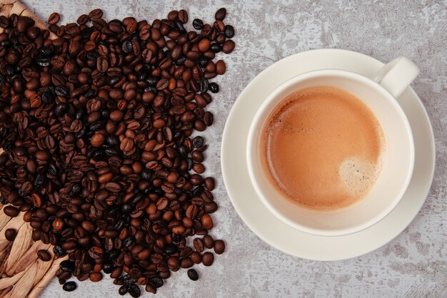 Encimera rústica de cemento con una taza de café y un puñado de granos de café.