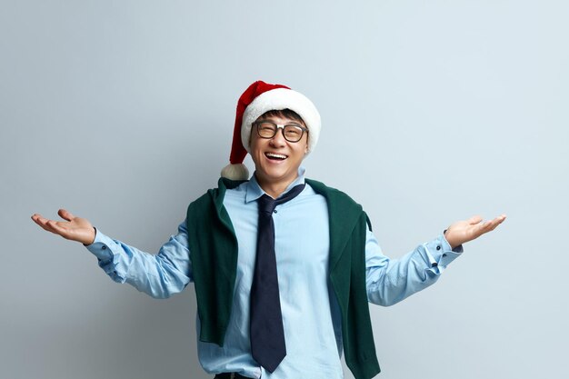 Encolhendo o homem sorridente Studio Guy com chapéu de Papai Noel em pé levantando as mãos