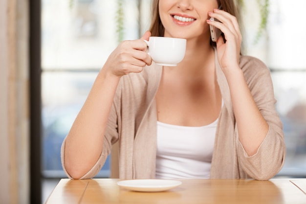 Encontrar tempo para ligar para amigos. Imagem recortada de uma bela jovem tomando café no restaurante e falando ao telefone