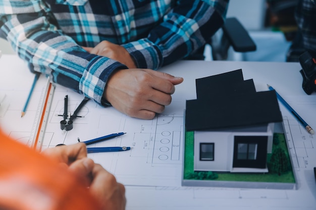 Encontro de engenheiros trabalhando e apontando para desenhos no escritório para discutir ferramentas de engenharia e conceito de construção