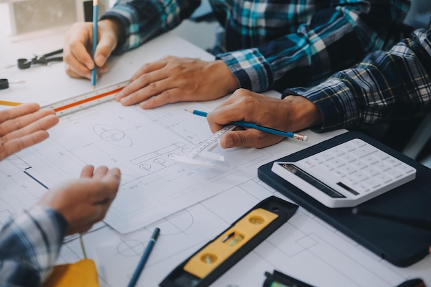 Encontro de engenheiros trabalhando e apontando para desenhos no escritório para discutir ferramentas de engenharia e conceito de construção