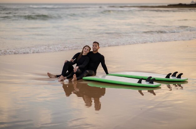 Encontro de surf jovem lindo casal relaxando na praia depois de surfar juntos