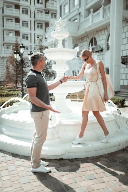 Encontro de verão. Casal feliz andando de mãos dadas perto da bela fonte no dia quente de verão.