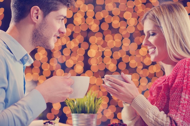 encontro romântico à noite no restaurante feliz casal jovem com copo de vinho, chá e bolo