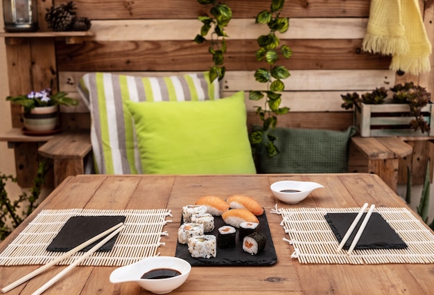 Foto encontro romântico para duas pessoas num jantar de sushi. mesa de madeira ao ar livre no terraço.