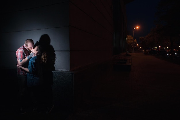 Foto encontro romântico secreto à noite casal de beijos relacionamentos proibidos adultério fundo de rua escura luz atmosférica conceito proibitivo