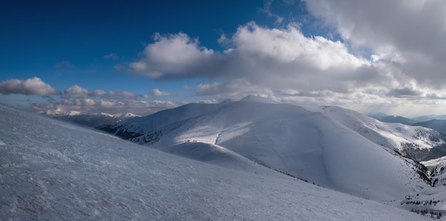 Encosta de montanha coberta de neve na luz do sol da noite passada Magnífico crepúsculo ventoso no topo acima da pitoresca estância de esqui alpina Dragobrat Ucrânia Carpathian Mountains