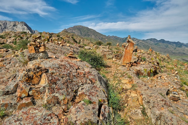 Encosta íngreme de montanha rochosa com arbustos e vista da cordilheira