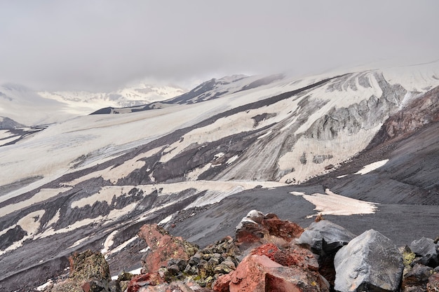 Encostas de montanhas e rochas vulcânicas pretas cobertas de neve.