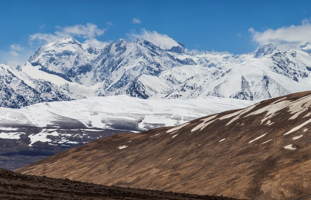 Encostas secas e picos cobertos de neve das montanhas Pamir no Tajiquistão