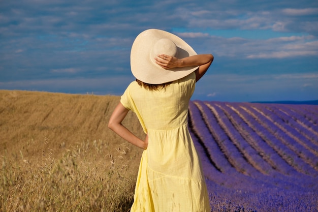 Encuentro de dos mundos: una niña con un vestido amarillo entre un campo de trigo y lavanda