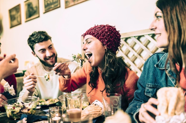 Encuentro de jóvenes divirtiéndose comiendo y bebiendo juntos en un pub - imagen filtrada vintage