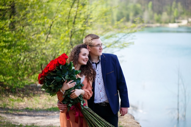 Encuentro romántico de jóvenes. Una joven accedió a casarse con su hombre. Un chico de traje con un ramo de rosas rojas le da un ramo a la niña y se besan en el bosque.