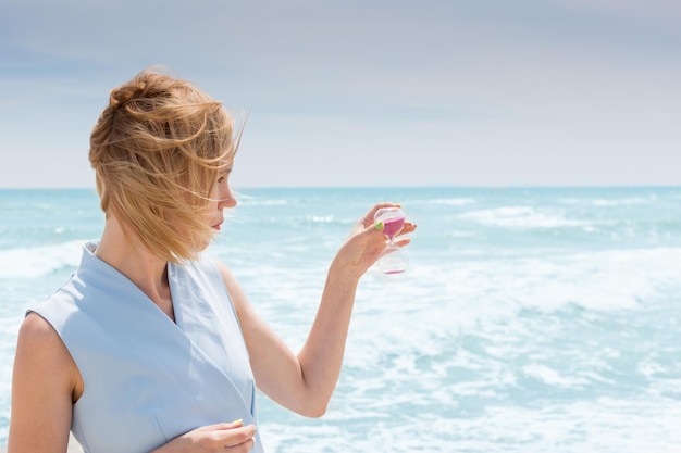 Ende des Urlaubs Eine Frau hält eine Sanduhr vor dem Hintergrund des Meeres, des Ozeans