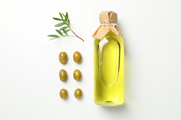 Endecha plana con botella de aceite de oliva, aceitunas y hojas en blanco, espacio para texto