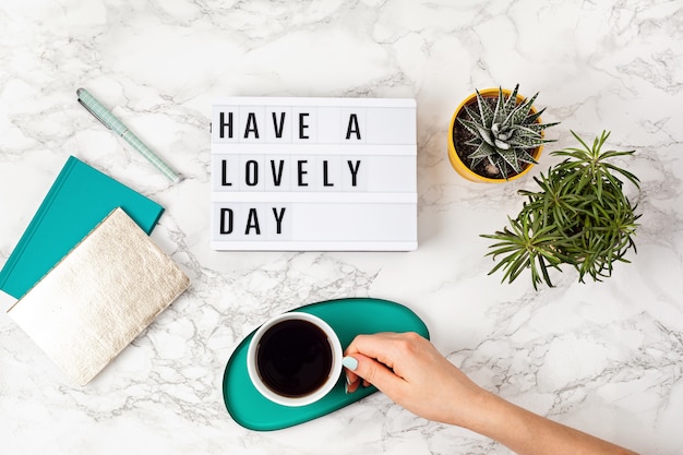 Foto endecha plana con caja de luz con texto que tengas un hermoso día y una taza de café. redes sociales, cita de motivación, blog femenino, concepto de la mañana del día laboral