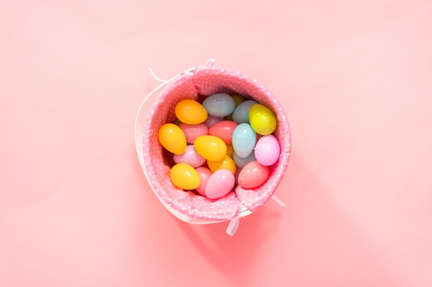 Endecha plana. Cesta de Pascua con huevos de Pascua sobre un fondo rosa.