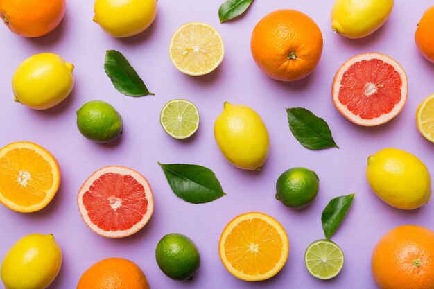 Endecha plana de cítricos como naranja lima y limón con hojas de limonero sobre fondo de color claro Espacio para texto concepto saludable Vista superior