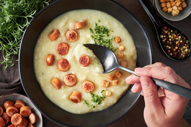 Endecha plana de crema de patata casera con crotones, salchichas de viena frita y cilantro verde