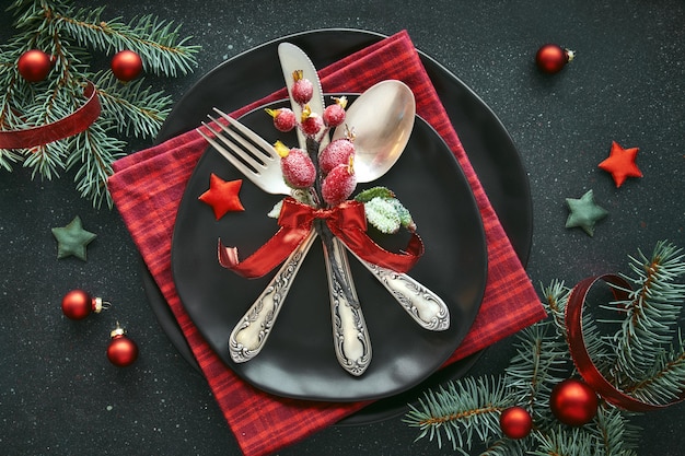 Endecha plana con decoraciones de Navidad en verde y rojo con bayas escarchadas, baratijas, platos y vajilla.
