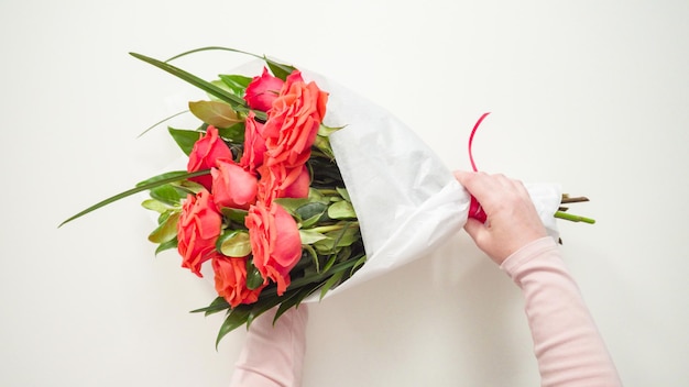 Endecha plana. Floristería envolviendo rosas rojas en un hermoso ramo.