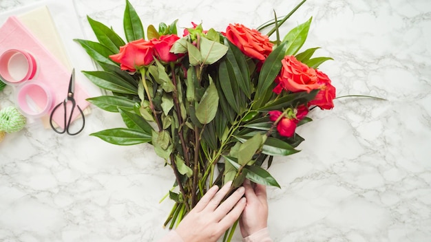 Endecha plana. Floristería podando rosas rojas para arreglos de ramo.