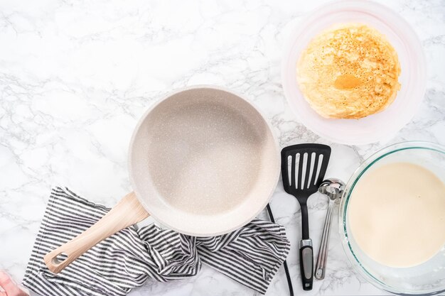 Endecha plana. Freír crepes en una sartén blanca.