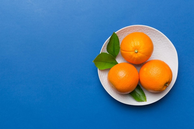 Endecha plana de fruta naranja fresca con rodajas en plato sobre fondo de color Vista superior con espacio de copia