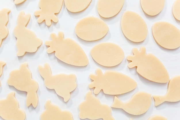 Endecha plana. Galletas de azúcar de Pascua sin hornear sobre una mesa blanca.