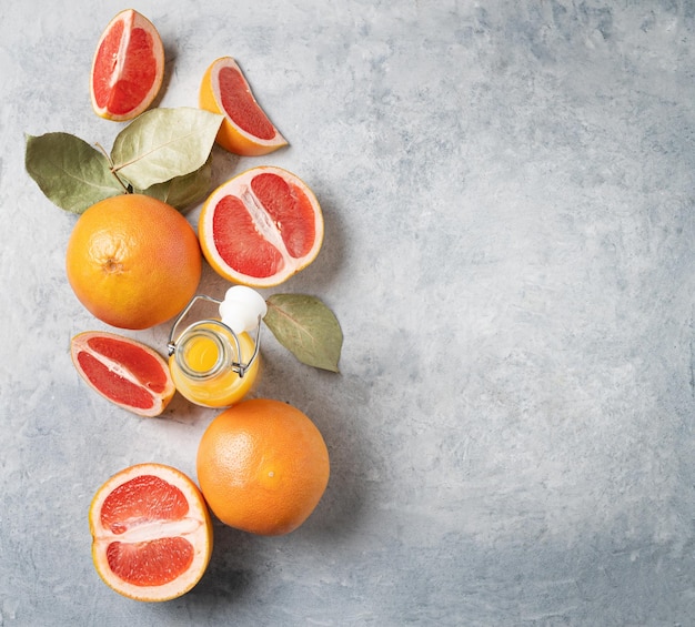 Endecha plana de jugosas toronjas rojas y jugo en una botella sobre un fondo azul. Concepto de alimentos saludables y dietéticos. Vista superior y espacio de copia.