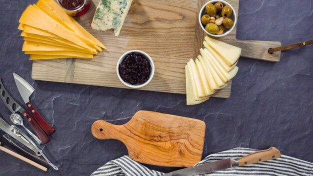 Endecha plana. Organizar queso gourmet, galletas saladas y frutas en una tabla para una tabla de quesos grande.