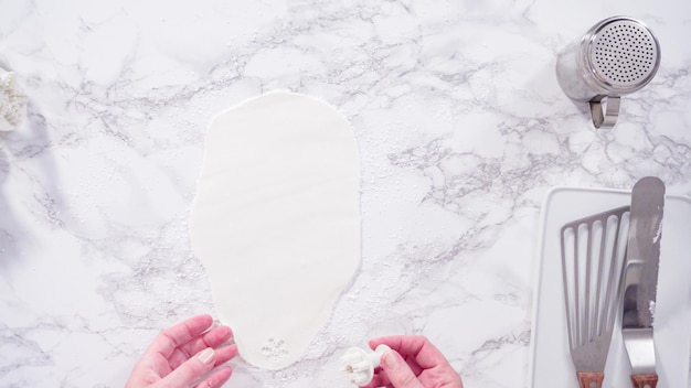 Endecha plana. Paso a paso. Cortar copos de nieve con cortadores de galletas de fondant blanco en un mostrador de mármol.