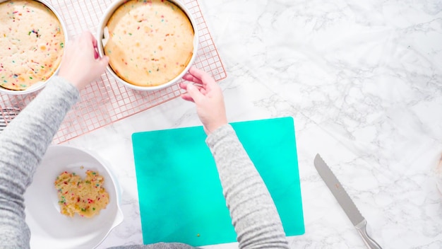 Endecha plana. Paso a paso. Envolver pastel funfetti recién horneado en celofán y papel de cocina para almacenar en el congelador.