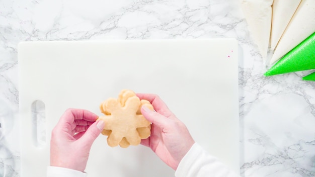 Endecha plana. Paso a paso. Glaseado de galletas de azúcar en forma de copo de nieve con glaseado rosa.