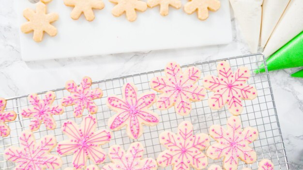 Endecha plana. Paso a paso. Glaseado de galletas de azúcar en forma de copo de nieve con glaseado rosa.