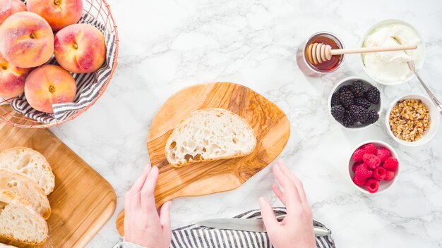 Endecha plana. Paso a paso. Hacer tostadas de ricotta con melocotones y bayas orgánicos.