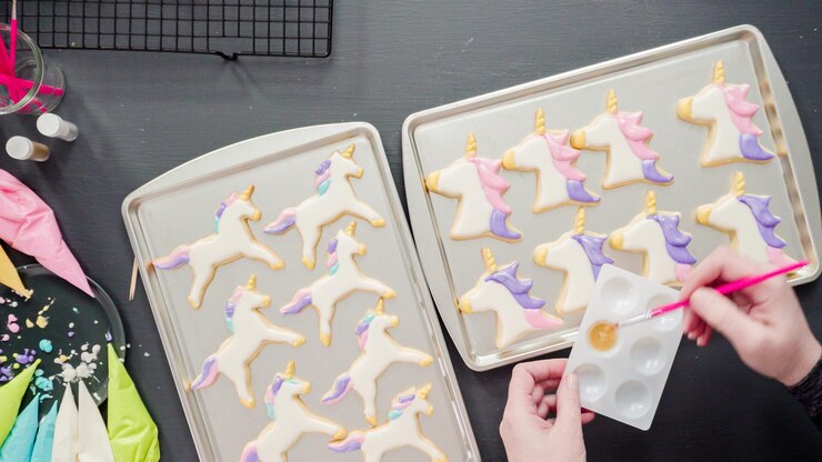 Foto endecha plana. paso a paso. pintar purpurina de comida encima de galletas de azúcar de unicornio con glaseado real.
