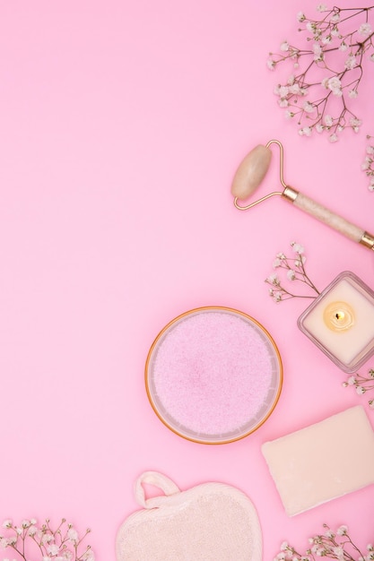 Endecha plana de productos cosméticos y de higiene y flores secas sobre un fondo rosa Concepto de spa Fondo de belleza copia espacio foto vertical