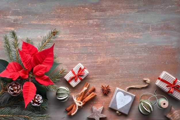 Endecha plana con ramas de abeto, poincettia y decoraciones de Navidad sobre fondo texturizado con espacio de copia.