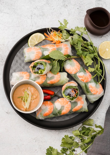 Endecha plana de rollos de camarones en un plato con salsa