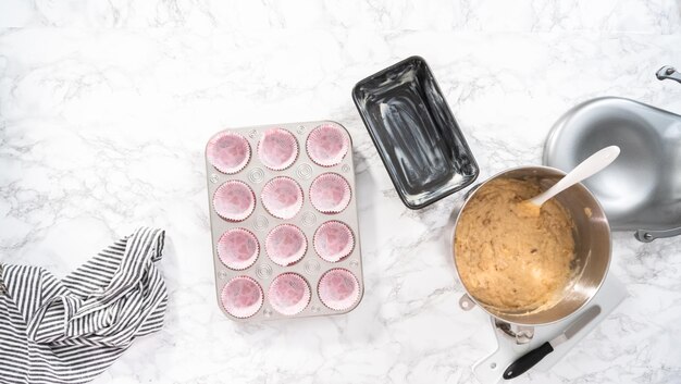 Endecha plana. Sacar la masa de pan de plátano en un molde para muffins para hornear muffins.