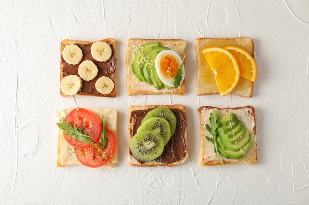 Endecha plana con sándwiches variados en blanco, vista superior