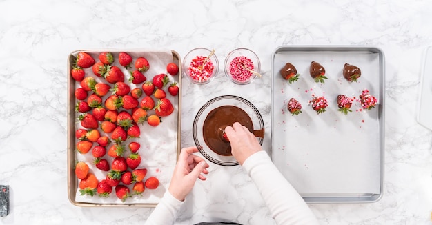 Endecha plana. Sumergir fresas en el chocolate derretido para preparar fresas cubiertas de chocolate.