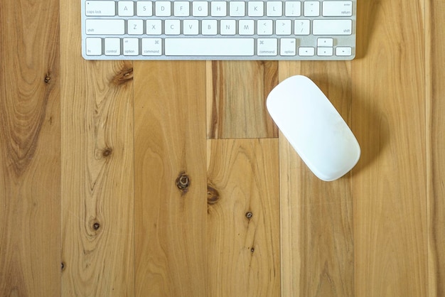 Endecha plana de teclado y mouse sobre una mesa de madera de pino