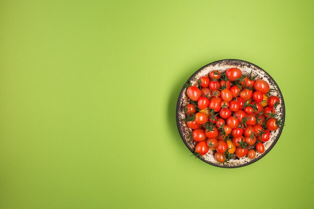 Endecha plana con tomates rojos sobre fondo verde.