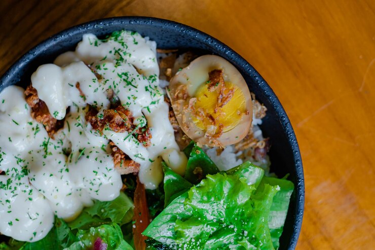 Endecha superior o plana de arroz con pollo con mayonesa, verduras y huevo cocido en la mesa de madera