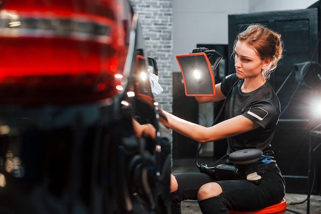 Endgültiges Polieren Modernes schwarzes Automobil wird von einer Frau in der Autowaschanlage gereinigt