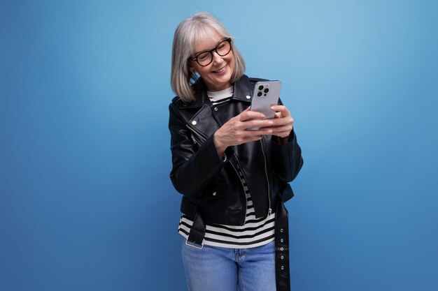 Energetic ist eine moderne Frau mittleren Alters mit grauem Haar, die mit dem Smartphone im Internet chattet