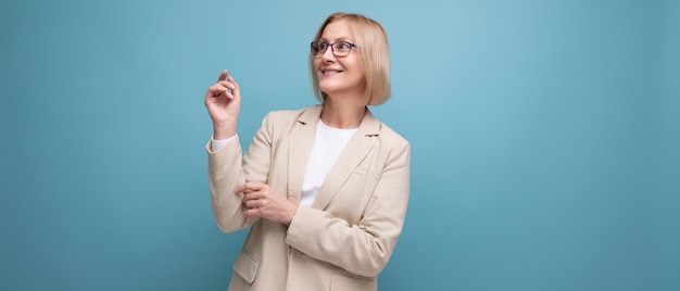 Energetische reife Frau in stylischer Jacke auf hellem Studiohintergrund mit Kopierraum