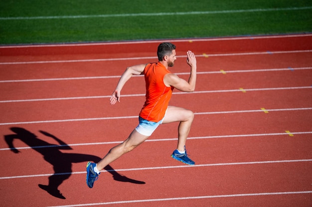 Energía adentro. corredor en pista. desafío y competencia. velocidad de maratón. atleta deportivo corre rápido para ganar. velocista de fitness exitoso. entrenador masculino en la pista de atletismo del estadio. resistencia y aguante.